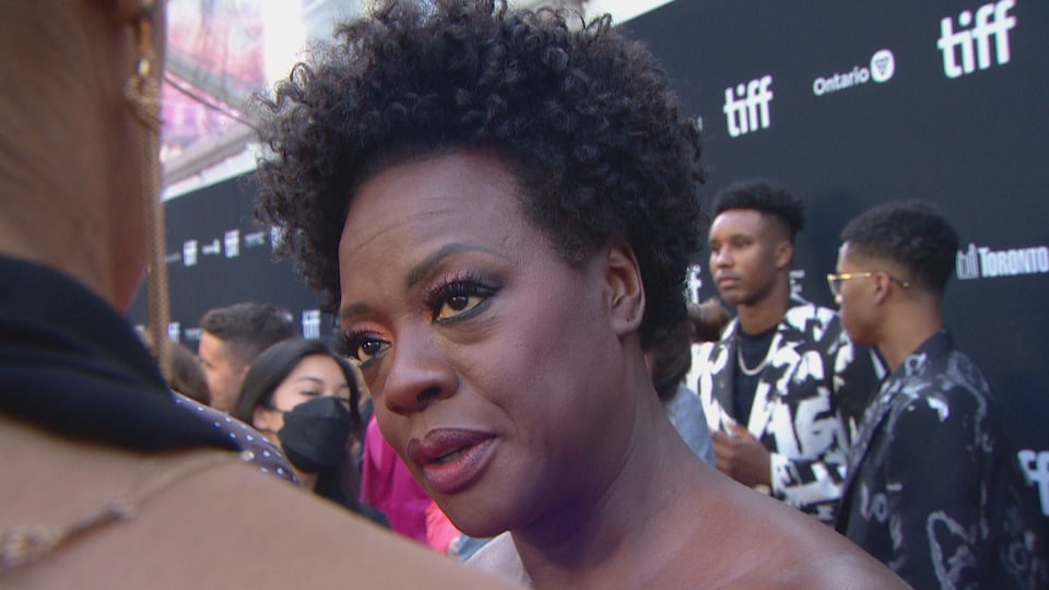 Viola Davis in evening dress answers questions from reporters on the red carpet.
