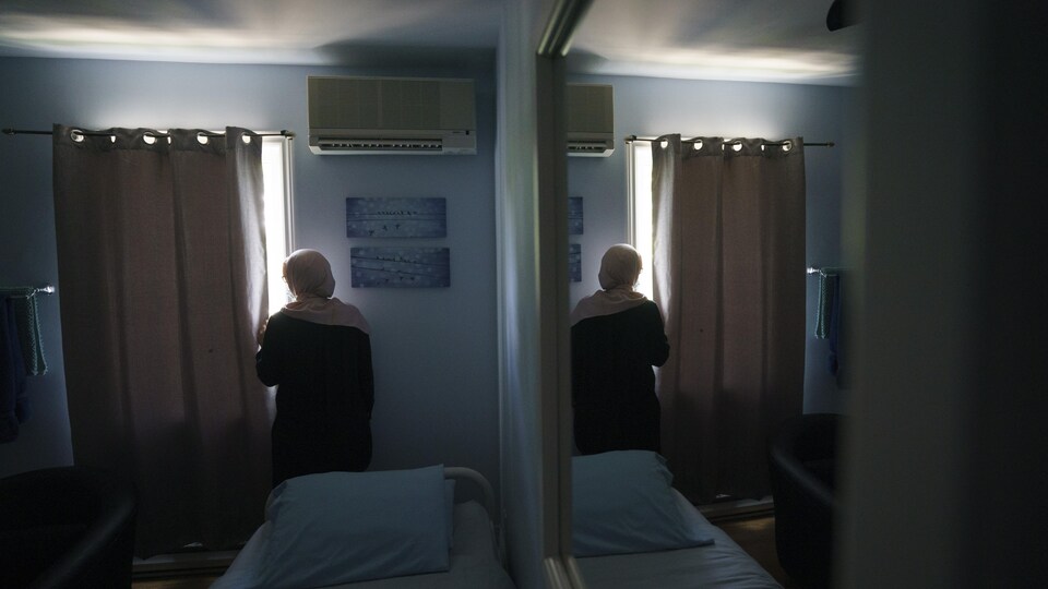 Nora regarde par la fenêtre dans sa chambre.