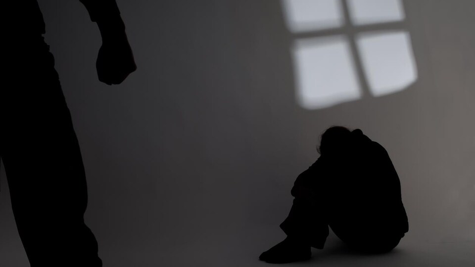 Une personne est assise par terre et une autre personne au premier plan a le poing serré.