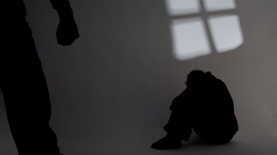 Une personne est assise par terre et une autre personne au premier plan a le poing serré.