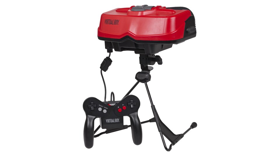 Une photo montrant le Virtual Boy de Nintendo sur un fond blanc. Il s'agit d'une paire de lunettes rouge ressemblant à un masque de réalité virtuelle monté sur un trépied. Une manette de jeu y est branchée.