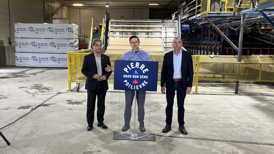 Three men in front of a platform in an industrial complex.