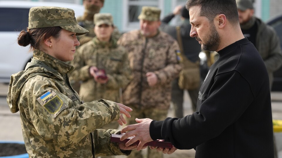 Une soldate reçoit une médaille des mains du président de l'Ukraine, Volodymyr Zelensky.