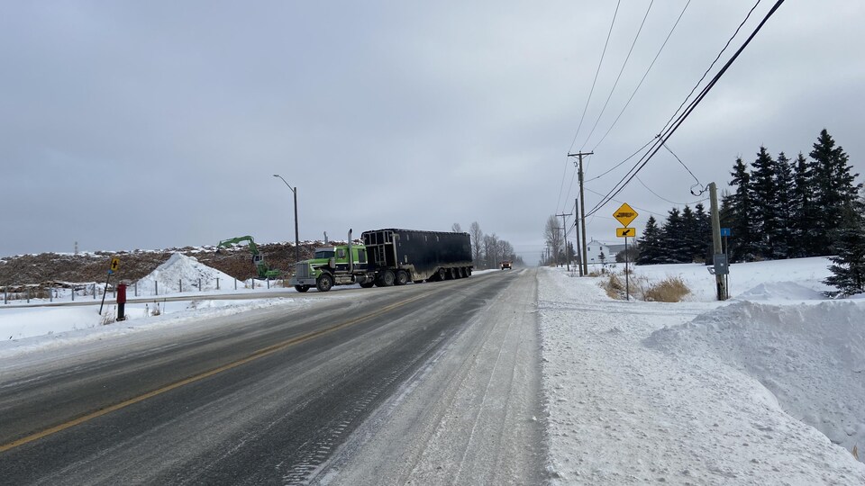 Un camion poids lourd sur la route tourne à droite pour entrer chez un producteur de bois.
