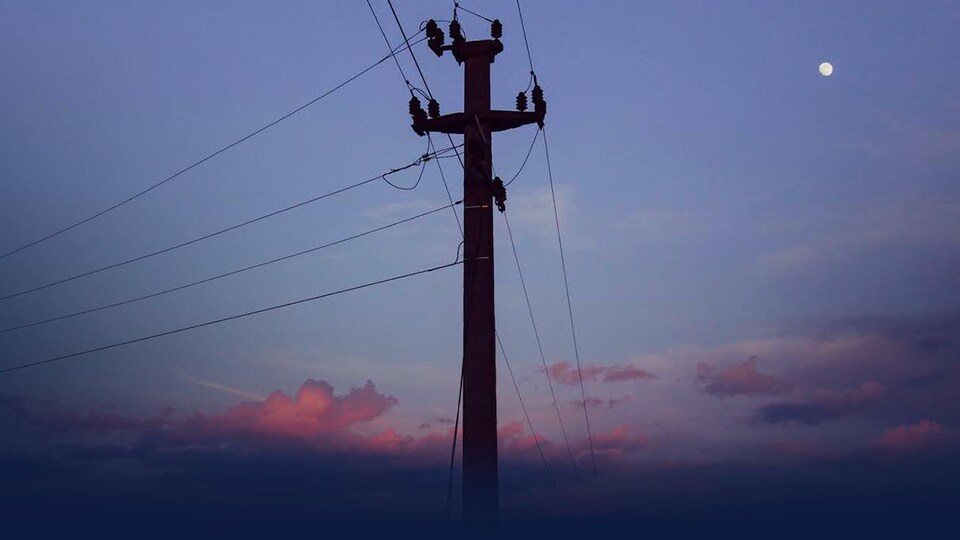 Un poteau de câbles sur fond de coucher de soleil