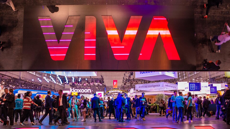 Une foule à un événement de la technologie avec les lettres « Viva » écrit en gros sur un mur. 