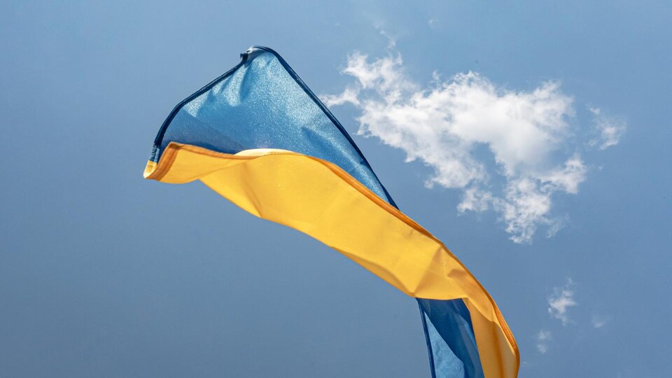 Le drapeau national de l'Ukraine vole au ventdans un ciel lumineux et ensoleillé.