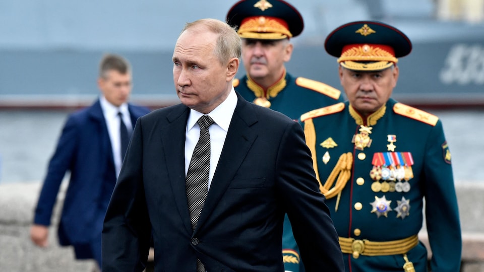 Vladimir Poutine marche devant des généraux militaires.