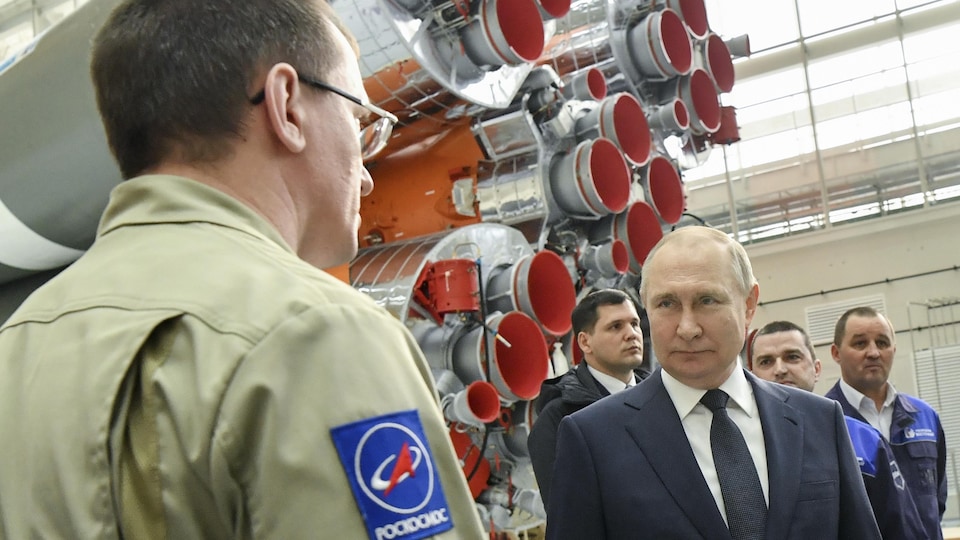 M. Poutine discute avec un homme près d'une fusée. 