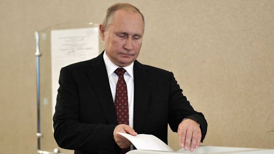 Vladimir Poutine place un bulletin dans une urne.