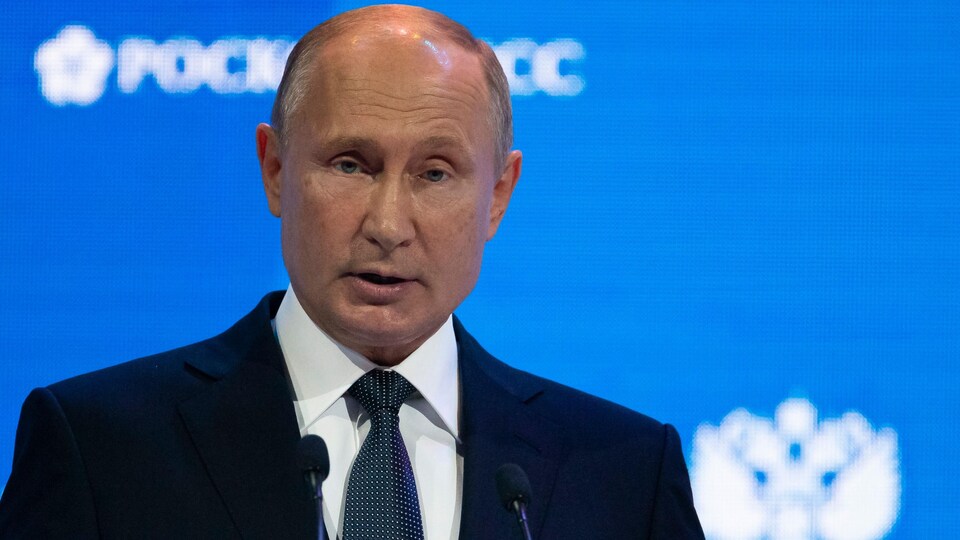 Vladimir Poutine parle au micro sur une tribune.