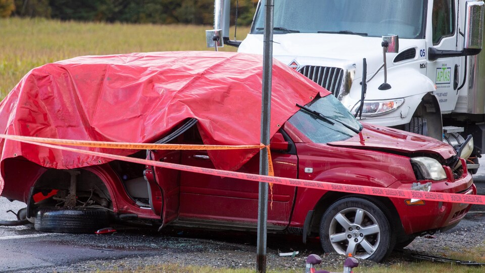 Une voiture rouge accidentée près d'un camion.