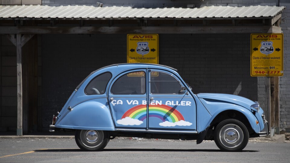 Une voiture ornée d'un arc-en-ciel et du message «Ça va bien aller».