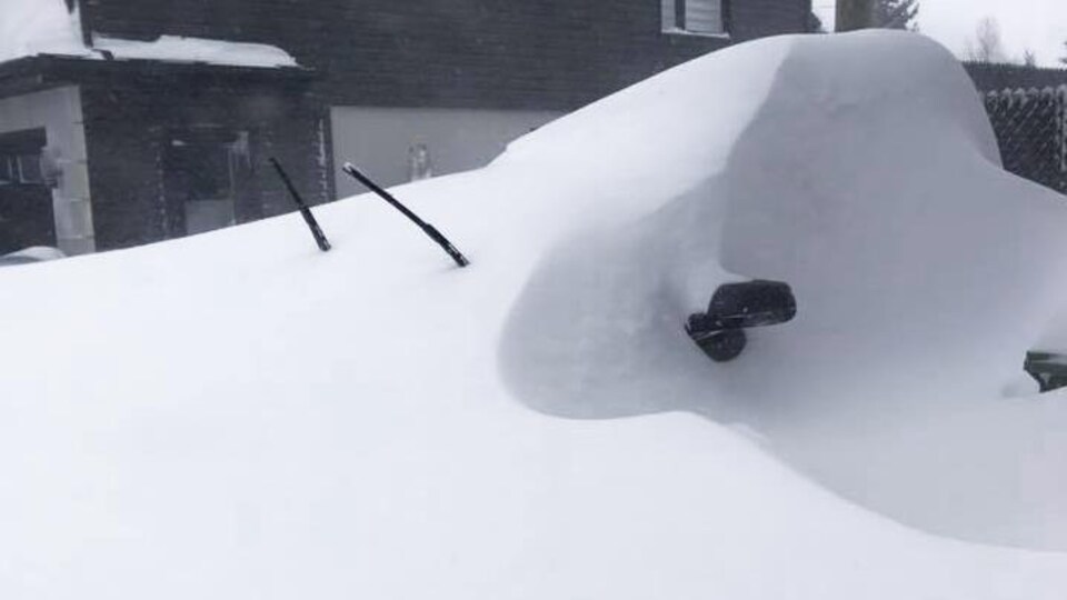 Une voiture ensevelie sous la neige.