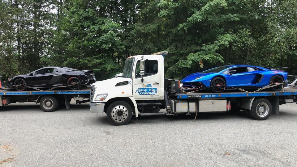 Une Lamborghini bleue et une  McLaren noire sur des camions de remorquage. 