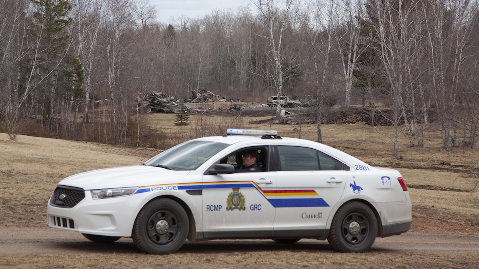Une voiture de la Gendarmerie royale du Canada devant des ruines.