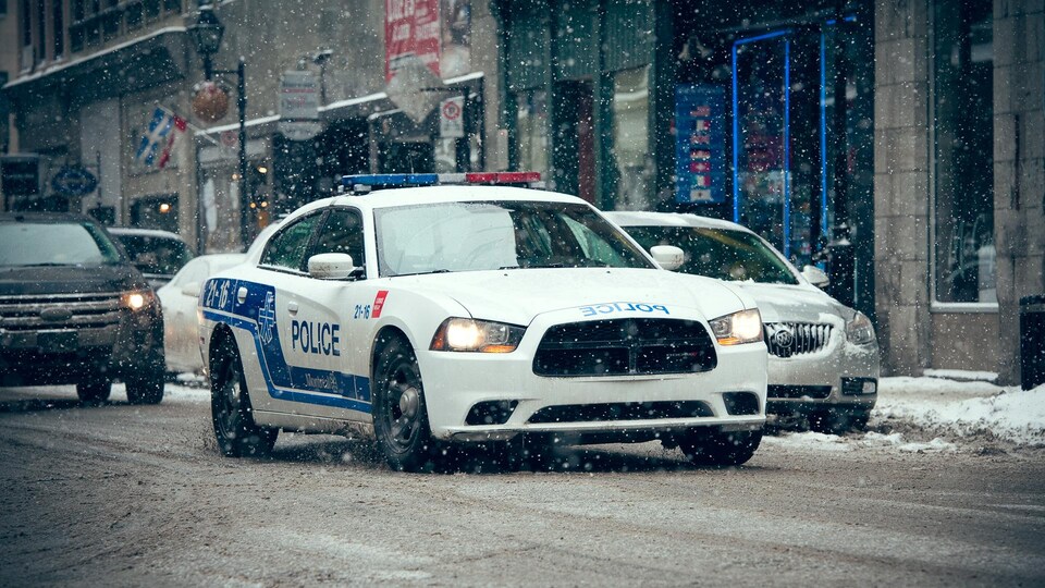 Une auto-patrouille du Service de police de la Ville de Montréal roule sous la neige.