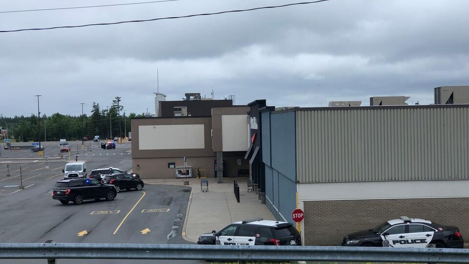Des voitures de police devant un centre commercial.