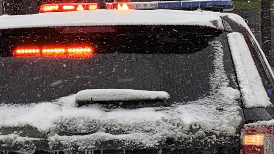 Une voiture de la Sûreté du Québec est stationnée. Les gyrophares fonctionnent.