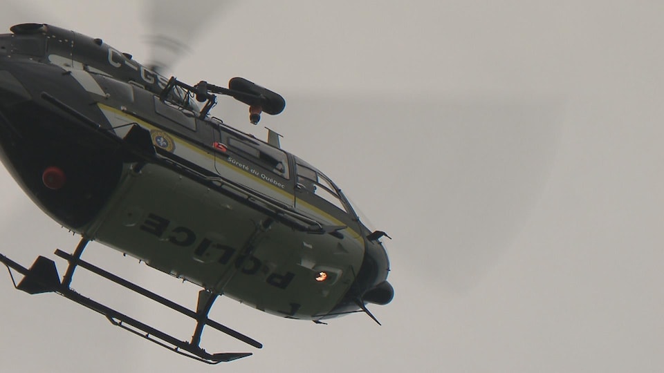 A Sûreté du Québec helicopter is flying over a search area.