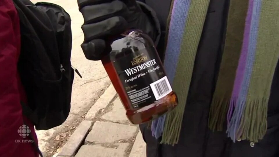 Un homme tient une bouteille de vin fortifié à la main.