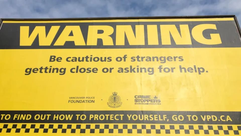 Un panneau publicitaire où l'on peut lire : attention, soyez vigilants lorsque des étrangers se rapprochent de vous ou vous demandent de l’aide.