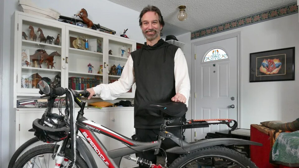 Tim Webster poses with his bike in his living room. 