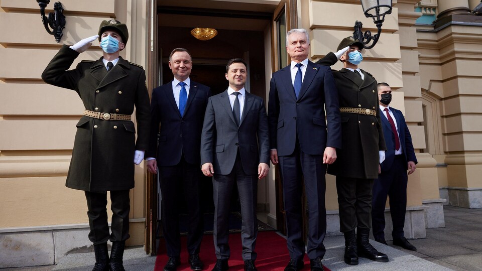 Volodymyr Zelensky, en compagnie Andrzej Duda et Gitanas Nauseda. aux côtés de deux hommes en uniforme au garde-à-vous.