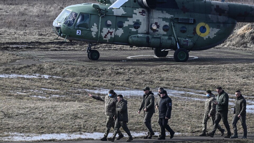 Le président marche près d'un hélicoptère avec des membres de l'armée.