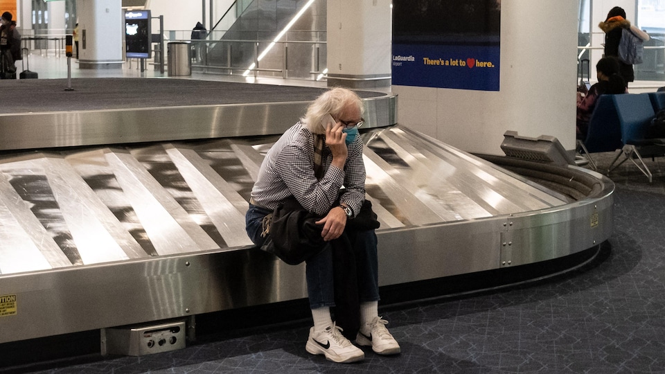 Un voyageur est assis à la récupération des bagages dans un aéroport.