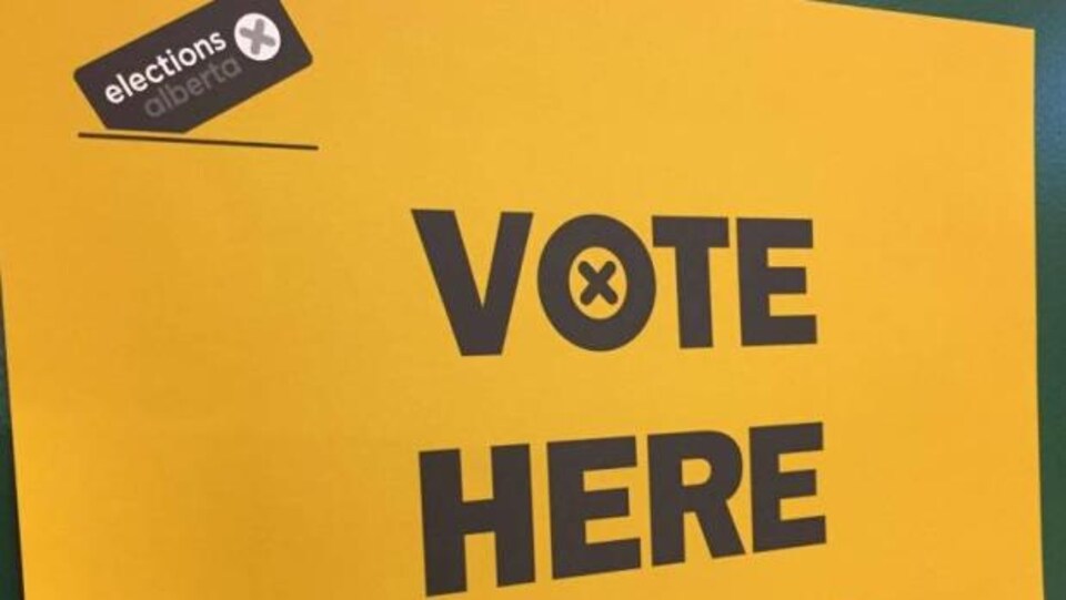 Plan serré d'une pancarte d'Élections Alberta où il est écrit en anglais « Votez ici ».