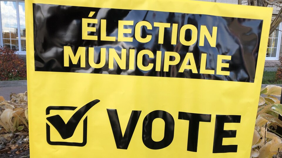 Gros plan sur une pancarte plantée dans le gazon annonçant « Élection municipale : vote ».