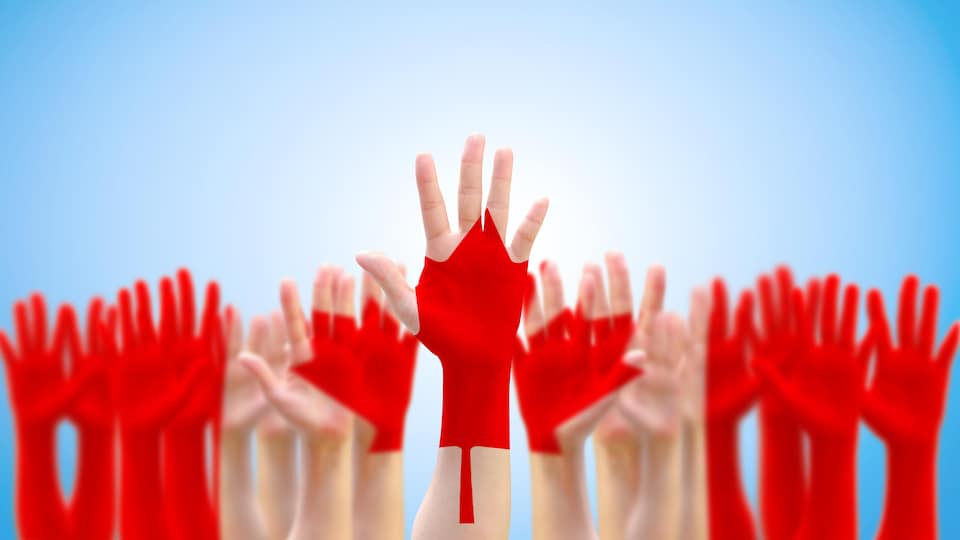 Des mains levées avec le motif d'un drapeau canadien en surimpression.