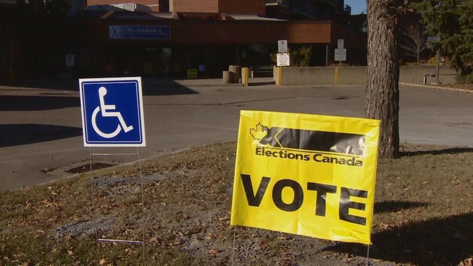 Une pancarte jaune sur laquelle il est inscrit : Élections Canada et Vote. À gauche, une pancarte bleue avec le symbole du handicap.
