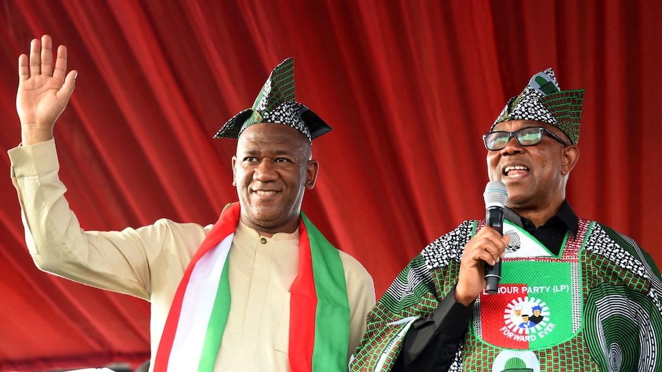 Les deux hommes portent les couleurs du Nigeria (blanc, vert et rouge) et un chapeau traditionnel.