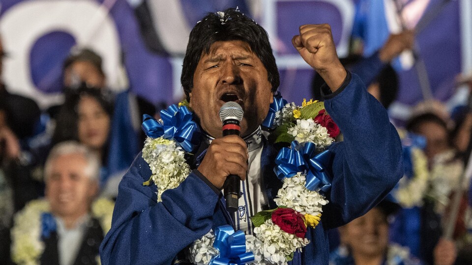 M. Morales, un collier fleuri autour du cou, lève le poing devant la foule.