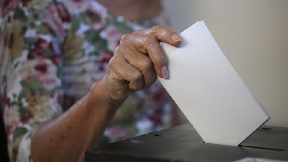 Une femme dépose son bulletin de vote dans une urne.