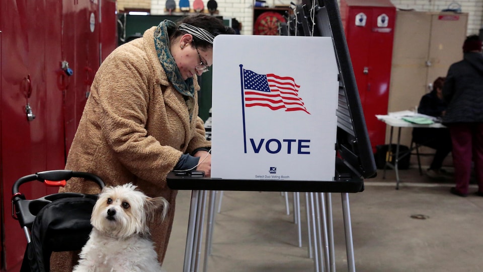 Une électrice vote avec son chien à ses côtés.