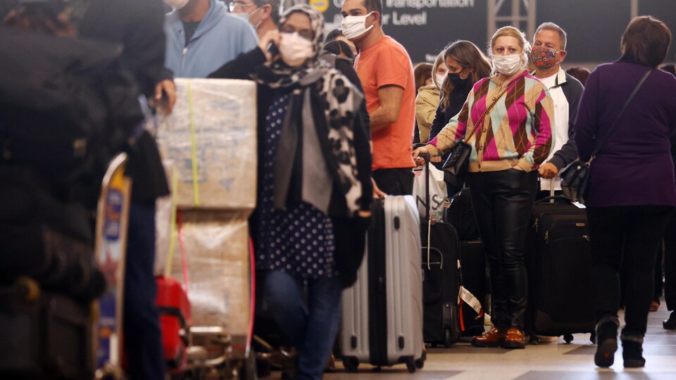 Une file de voyageurs attendent en ligne à l'aéroport.
