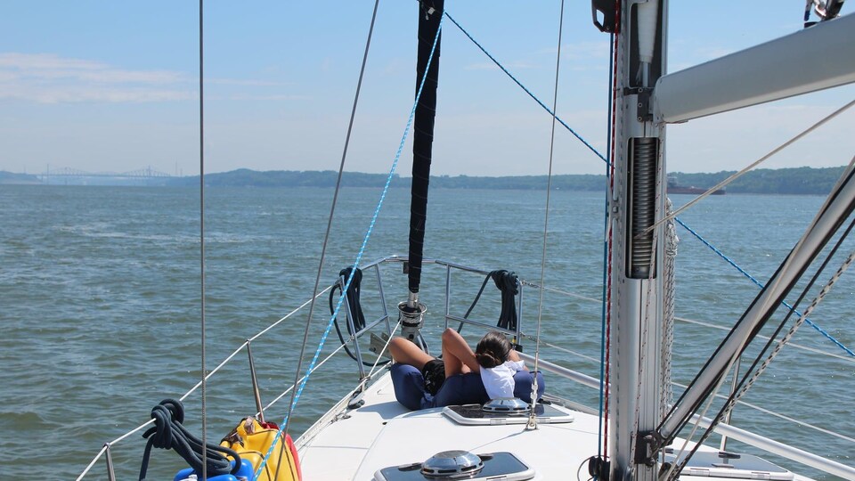 A man is lying in a boat and watching the open sea.