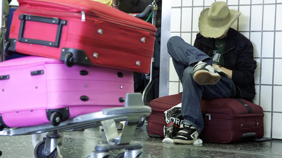 Un voyageur attend son vol dans un aéroport. 