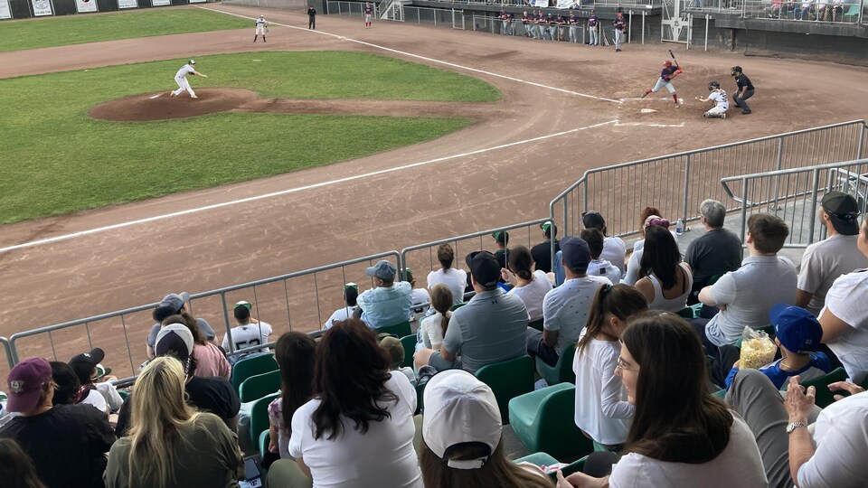 Un match de baseball junior devant des estrades garnies.