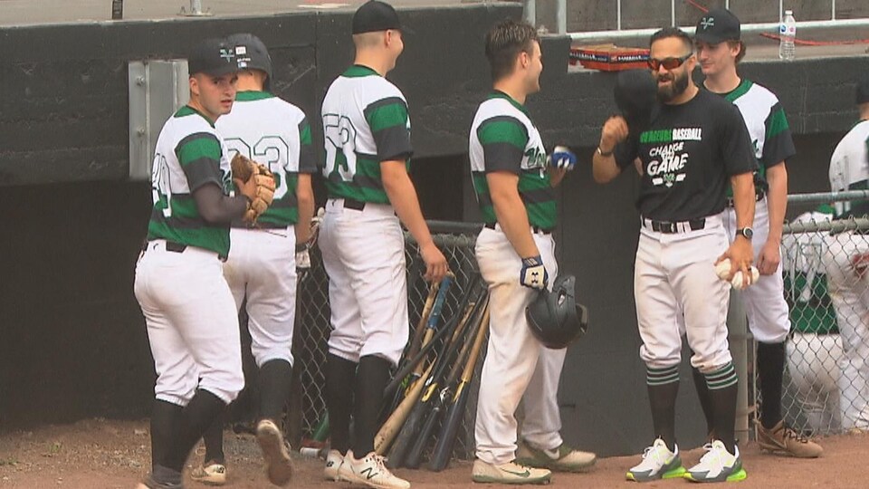 Des joueurs de baseball se trouvent à deux pas de leur abri.