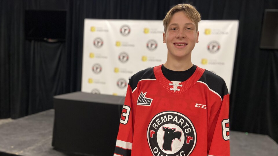 Un joueur de hockey pose dans un gilet des Remparts.