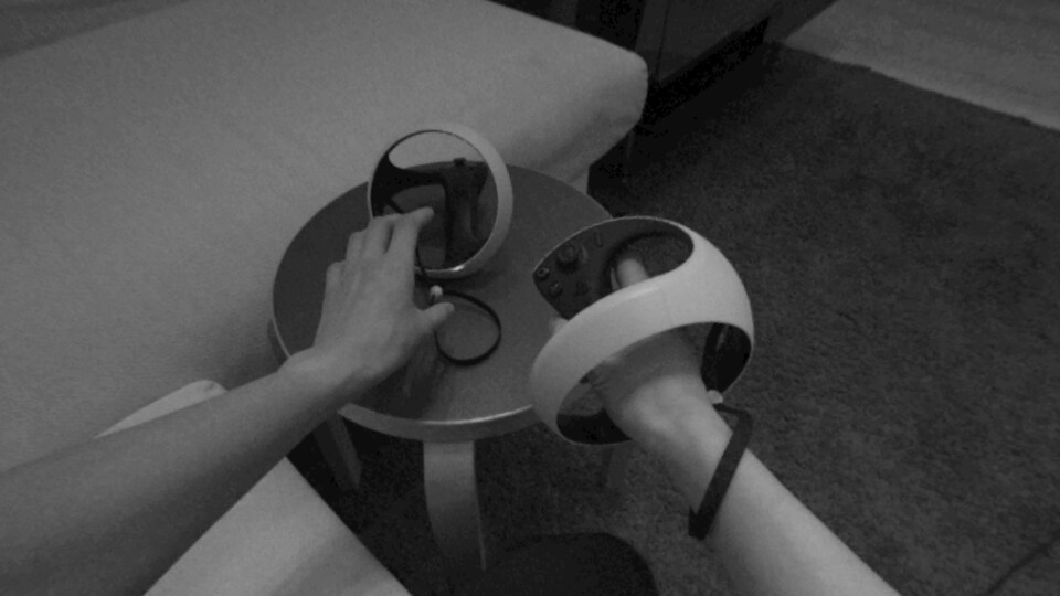 Vue à la première personne d'une personne qui tend ses mains vers des manettes de PS VR2 posées sur un tabouret.