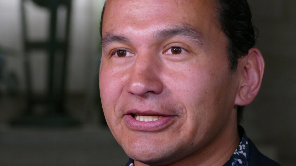 Gros plan sur le visage de Wab Kinew, un homme autochtone assez jeune, en train de parler lors d'une conférence de presse.