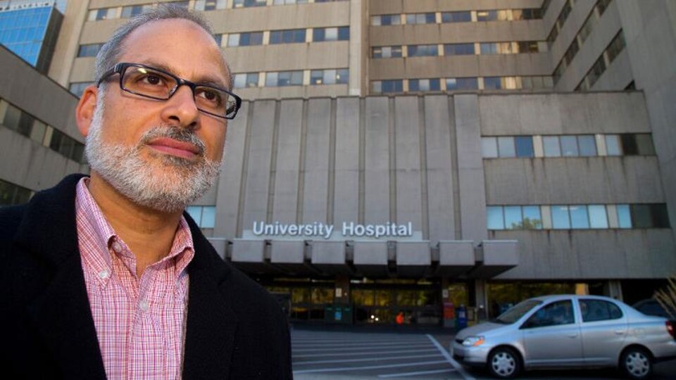 Le médecin portant des lunettes devant un hôpital.