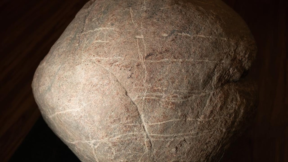 Une pierre de forme ronde sur laquelle sont tracées des stries.