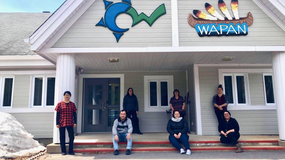 Des gens posent devant l'affiche de Wapan.