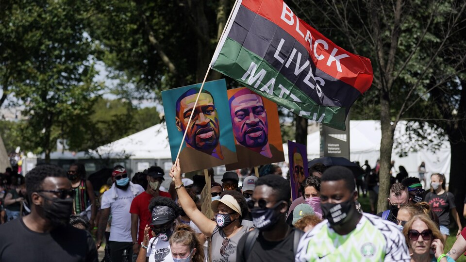 Des manifestants brandissent la photo de George Floyd et des banderoles sur lesquelles il est écrit : Black Lives Matter